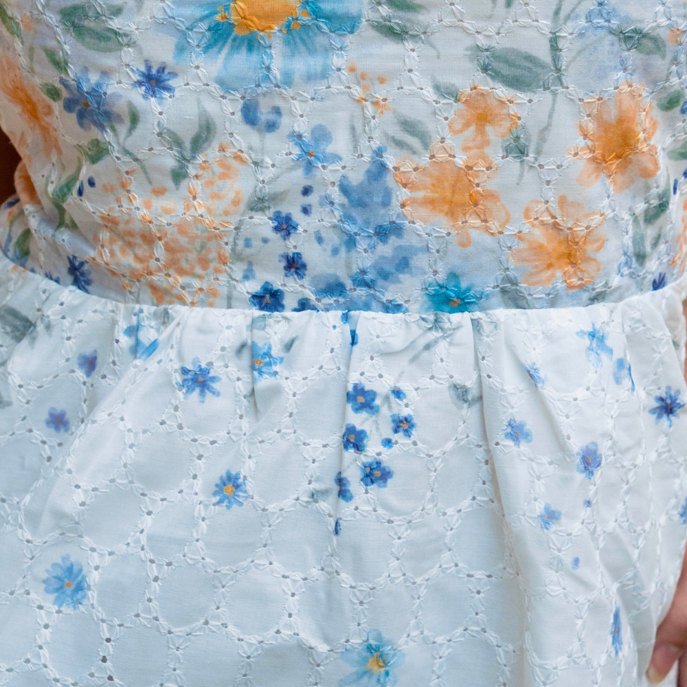 Clarisse Off Shoulder Maxi Dress White Blue — close-up of blue floral broderie anglaise embroidery and frill detail | La Mira Singapore
